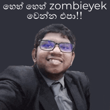 a man wearing glasses and a suit is smiling in front of a sign that says zombievek