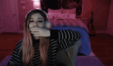 a girl wearing headphones waves her hand in front of a bed