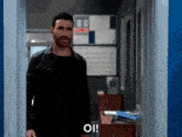 a man in a black jacket is standing in a doorway with the word oi written on it .
