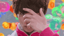 a person in a pink jacket is covering their face with their hands