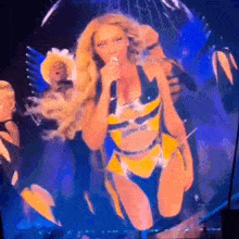 a woman in a yellow and black outfit is singing into a microphone on stage .