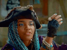 a woman wearing a pirate hat and gloves looks at the camera