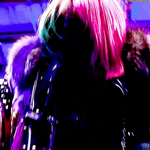 a woman with pink hair is wearing a black and purple coat