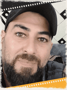 a man with a beard is wearing a black hat and a black jacket