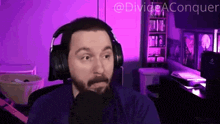 a man wearing headphones is sitting in front of a microphone with the words divide aconquer written in the corner