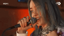 a woman singing into a microphone with ntr written on the bottom