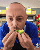a man in a blue shirt is eating a green object