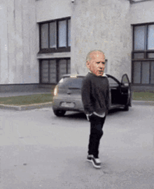 a man with a big head is walking down the street in front of a car