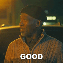 a man wearing a hat and sweater is smiling and says good