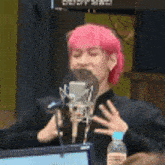 a woman with pink hair singing into a microphone