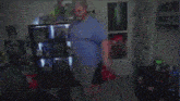 a man in a blue shirt is dancing in a room with posters on the wall