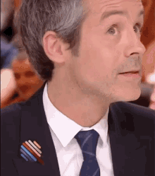 a man wearing a suit and tie has a rainbow pin on his lapel