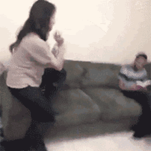 a woman is sitting on a couch while a man sits on a couch in a living room .