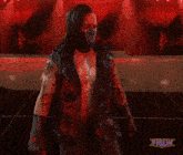 a man wearing a mask and a vest with spikes is standing in front of a sign that says tnlw