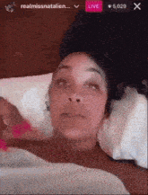 a woman is laying in a bed with a live button visible