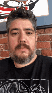 a man with a beard is wearing a black shirt with a circle design on it