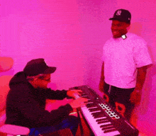 a man in a ny hat stands next to a man playing a keyboard