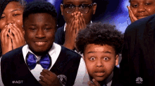 a group of young boys are covering their mouths with their hands while watching a show called agt on nbc
