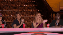 a group of people are sitting at a table with coca cola cups in front of them