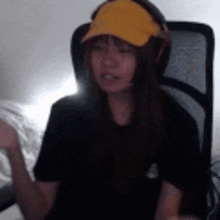 a woman is sitting in a chair wearing headphones and a hat .