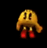 a close up of a pac man cartoon character with red feet and arms on a black background .