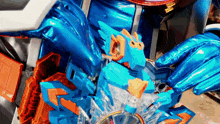 a close up of a blue and orange toy with a clock on it