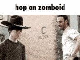 a man in a cowboy hat is standing next to another man in front of a brick wall that says c block .
