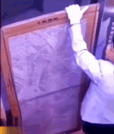 a person in white gloves is holding a large painting in their hands