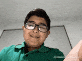 a young boy wearing glasses and a green polo shirt is smiling