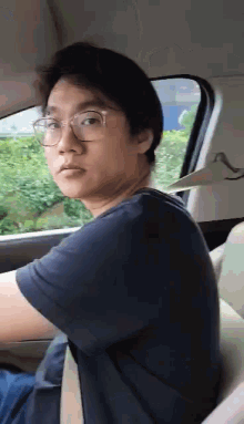a man wearing glasses is sitting in a car looking out the window .