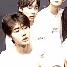 a group of young men are standing next to each other and looking at something .
