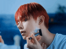 a man with red hair shaving his face with a razor