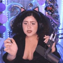 a woman wearing headphones and a cat ear headband is sitting in front of a microphone