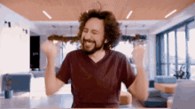 a man with a beard is raising his arms in the air in a room .