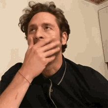 a man is covering his mouth with his hand while wearing headphones .