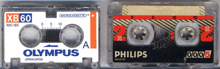 a philips cassette tape is next to an olympus cassette tape