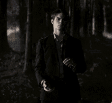 a man in a suit and tie stands in the dark