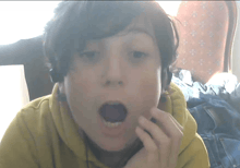 a young boy wearing headphones looks surprised with his mouth wide open