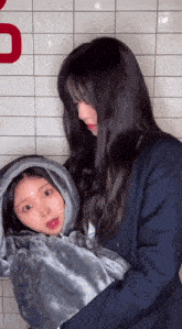 a woman is holding a child wrapped in a blanket with a hood