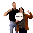 a man in a jumbo shirt stands next to a woman who is holding a sign that says bedankt