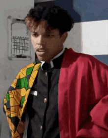 a man wearing a red jacket and a black shirt is standing in front of a calendar