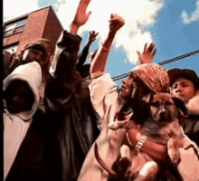 a group of people with their hands in the air including a dog