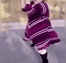 a woman in a purple and white striped dress is dancing on the ice .