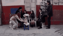 a group of people are sitting around a blender with the letter p on the wall behind them
