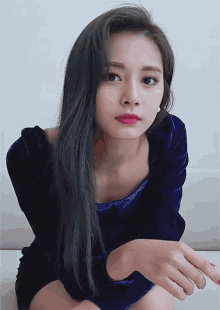 a woman in a blue velvet dress is sitting on a couch