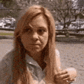 a woman with long blonde hair is looking at the camera while holding a cell phone .