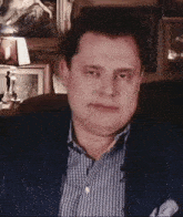 a man in a blue jacket and plaid shirt is sitting in a chair