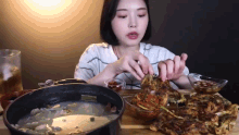 a woman is sitting at a table eating food from a bowl