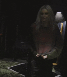 a woman in a sweater is standing in a dark room .