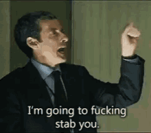 a man in a suit and tie is screaming and saying i 'm going to fucking stab you .